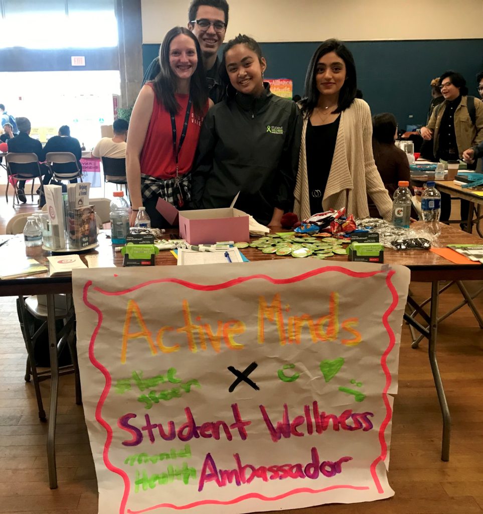Student Wellness Ambassadors standing and smiling behind event table